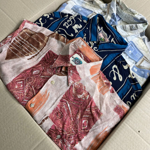 Tre camicie vintage anni 90 di diversi colori e fantasie all'interno di una scatola di cartone